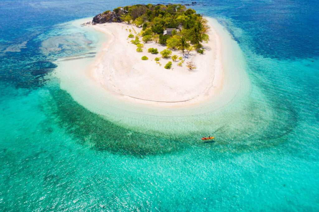 Tropical beach in Coron, Philippines _ Couple kayaking on a tropical beach with blue water and palm trees - Coron, Philippines