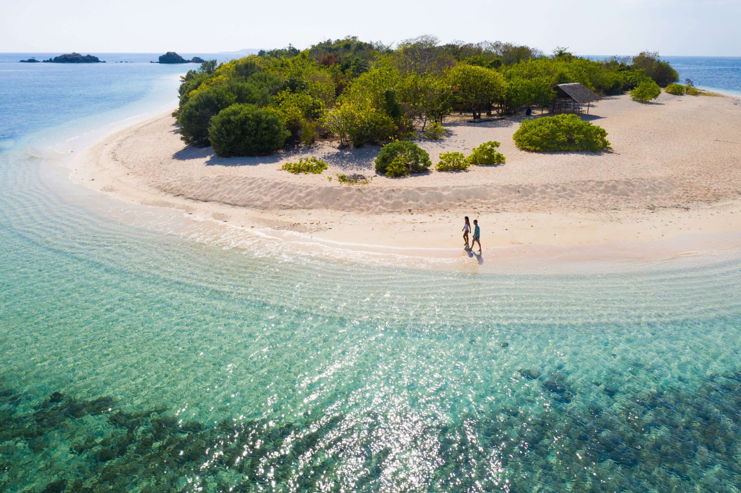 Couple on a tropical beach with blue water and palm trees - Coron, Philippines